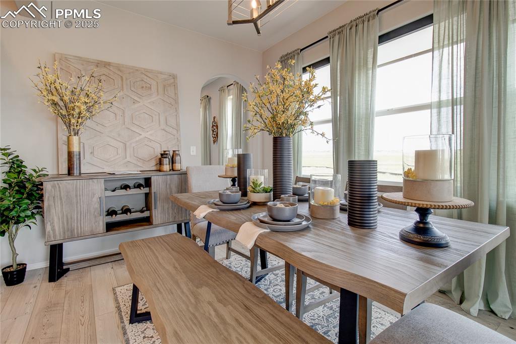 Image 9 of 25: Dining area with arched walkways and light wood-style flooring
