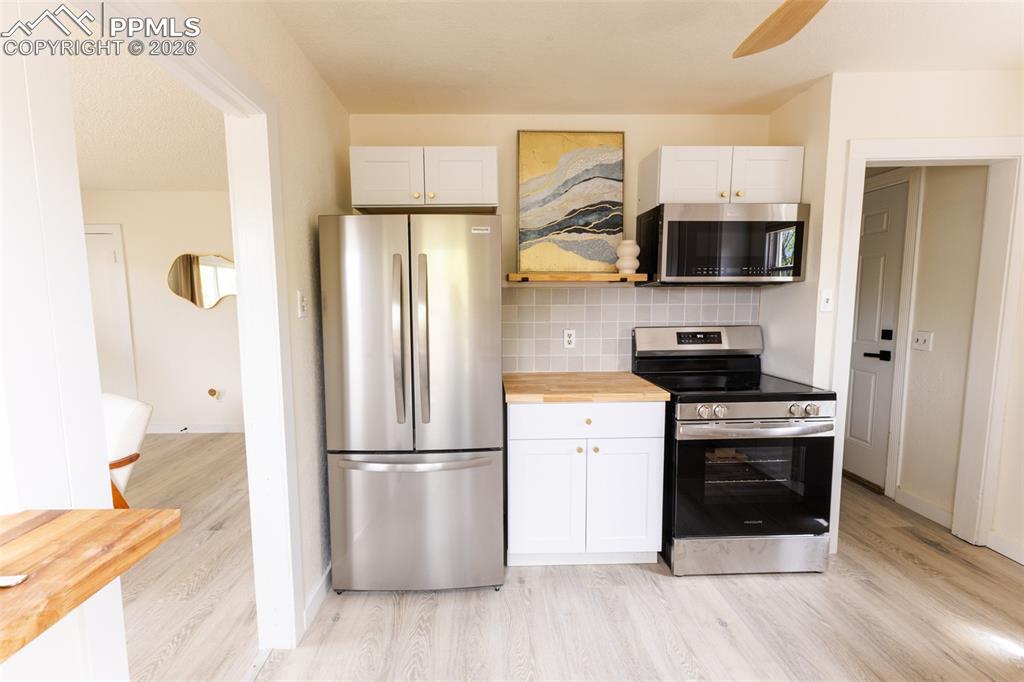 Image 10 of 24: Kitchen featuring stainless steel appliances, white cabinetry with gold-ton