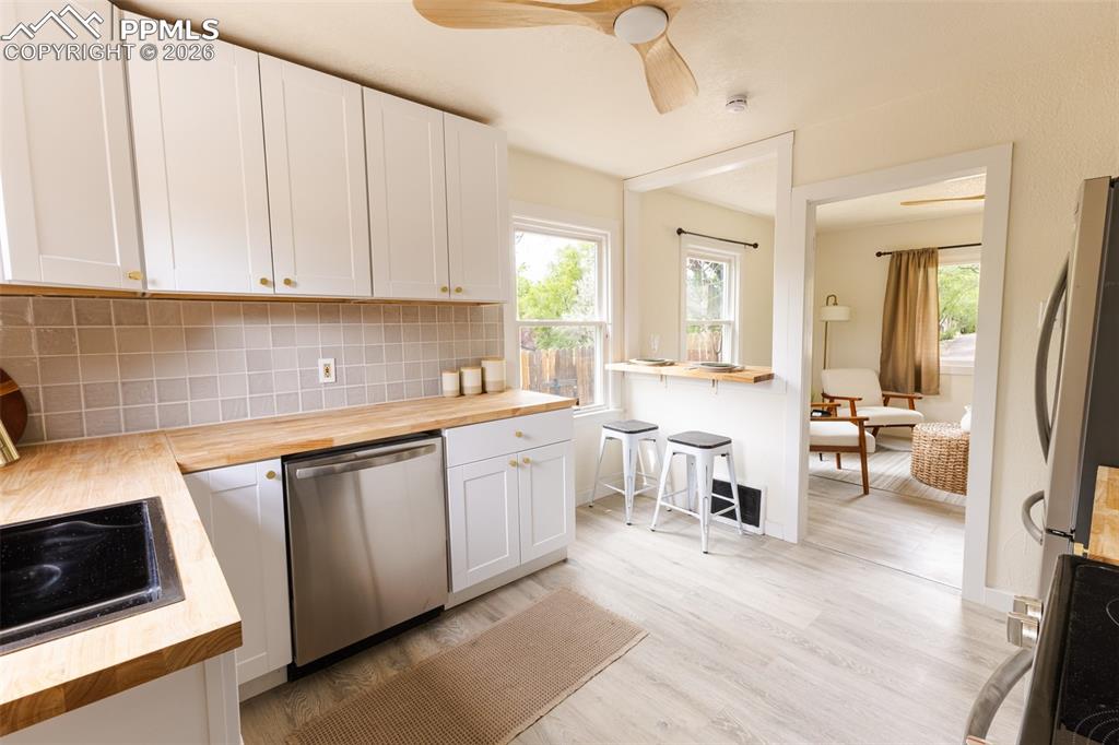 Image 11 of 24: Well-appointed kitchen featuring white cabinetry, light wood-finish counter