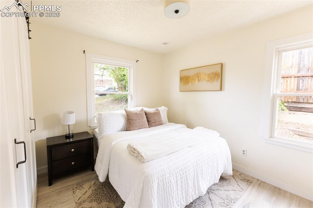 Image 14 of 24: Light-toned room featuring two windows, pale wood-finish flooring, a white 