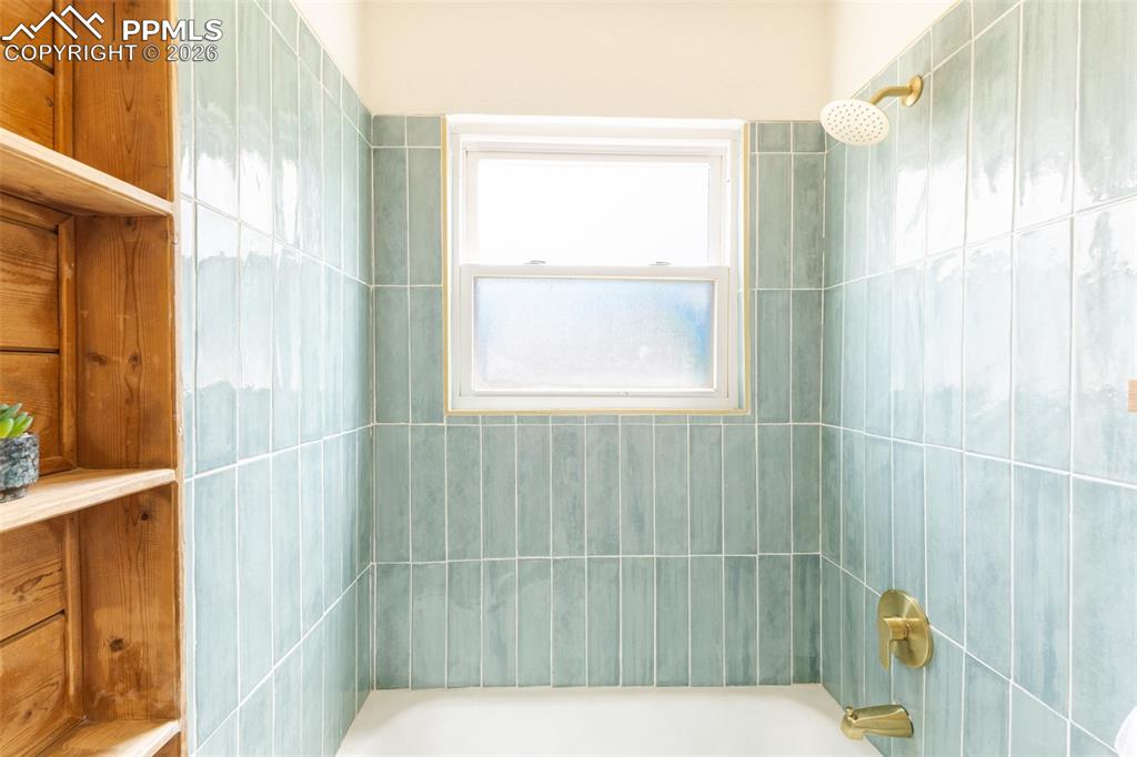 Image 20 of 24: Tub and shower combination featuring floor-to-ceiling green subway tile sur