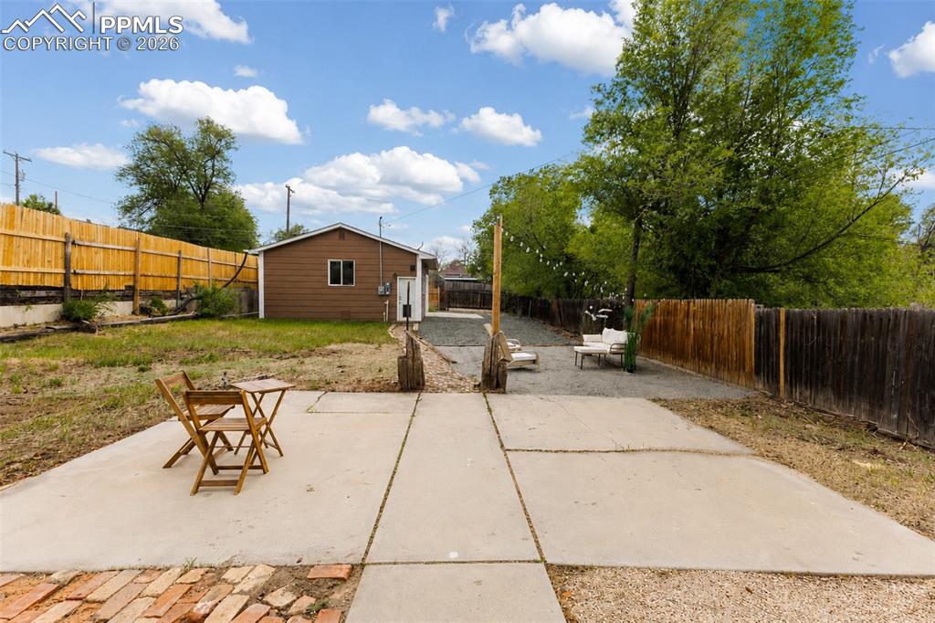 Image 21 of 24: Expansive backyard featuring a large concrete patio, gravel hardscaping, a 