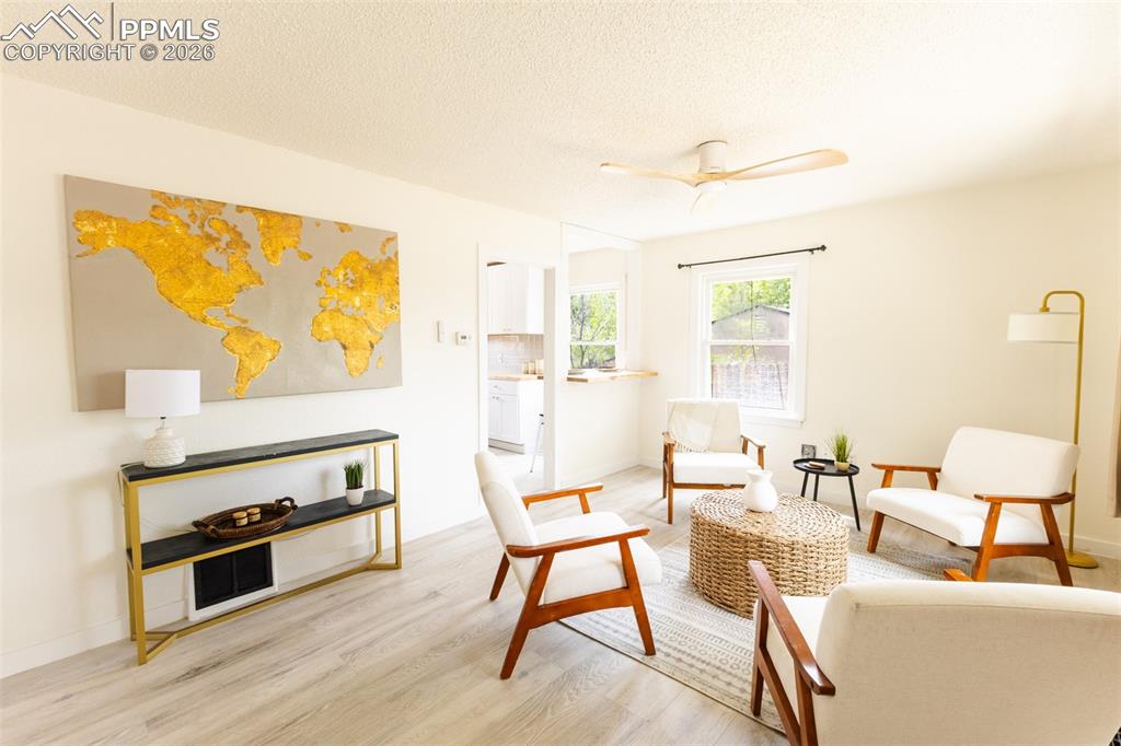 Image 4 of 24: Bright living space featuring light wood-finish flooring, white walls, and 
