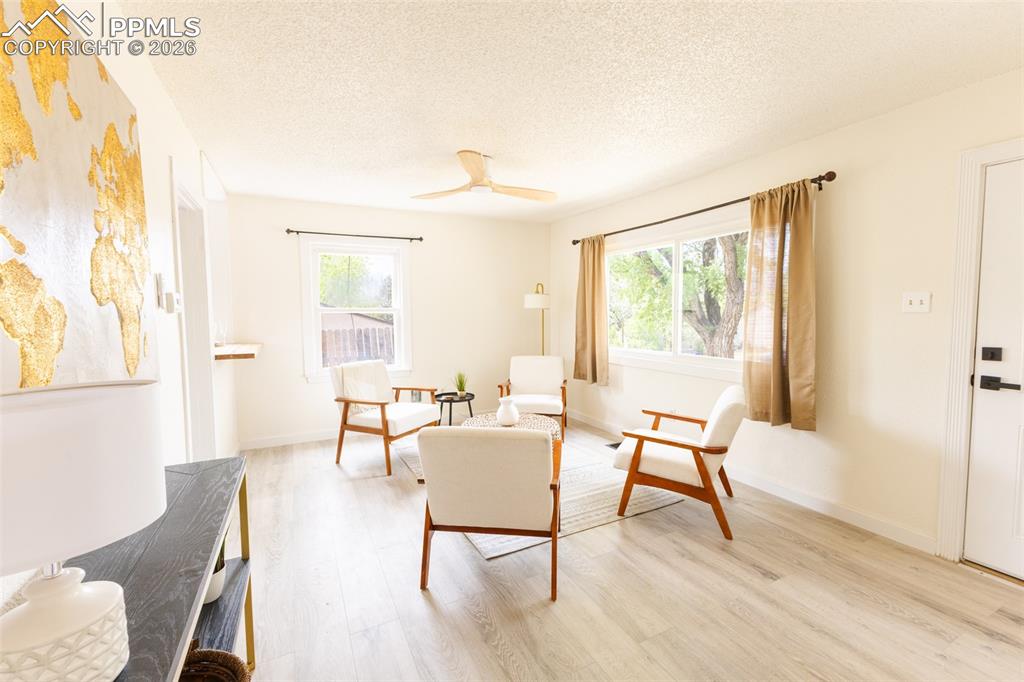 Image 5 of 24: Spacious living area featuring wood-finish flooring, a ceiling fan, and amp