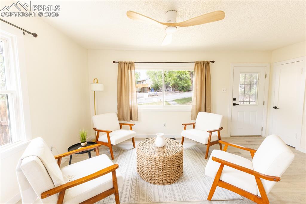 Image 6 of 24: Living area featuring light-toned walls, wood-finish flooring, and a ceilin