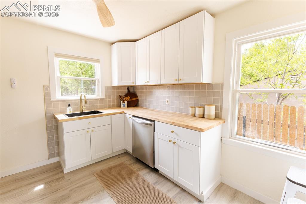 Image 9 of 24: Modern kitchen featuring white shaker cabinetry, light wood-finish countert