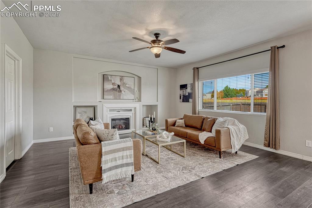 Image 5 of 50: Living room with ceiling fan, fireplace, and built-in shelving