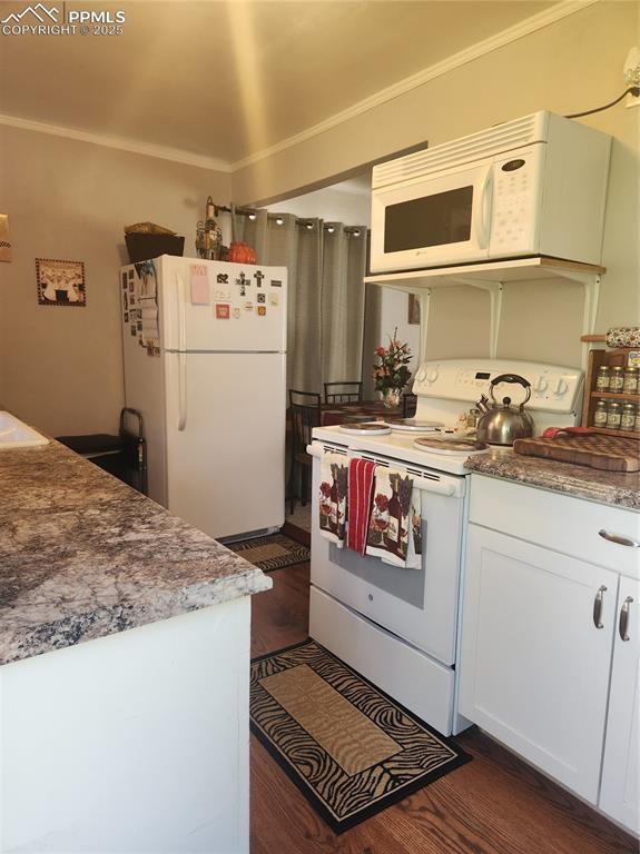 Image 3 of 10: Kitchen with white appliances, white cabinetry, dark wood-style floors, and