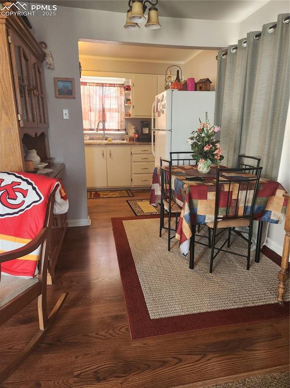 Image 5 of 10: Dining area featuring dark wood-style floors and baseboards