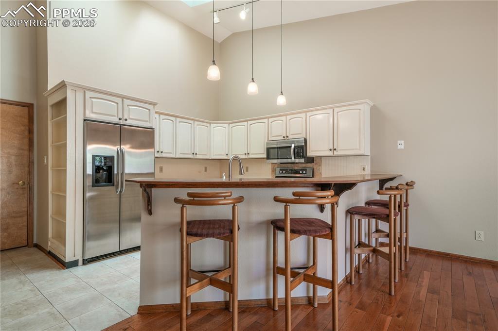 Image 12 of 50: Kitchen with additional bar seating, hard wood floors, updated appliances a