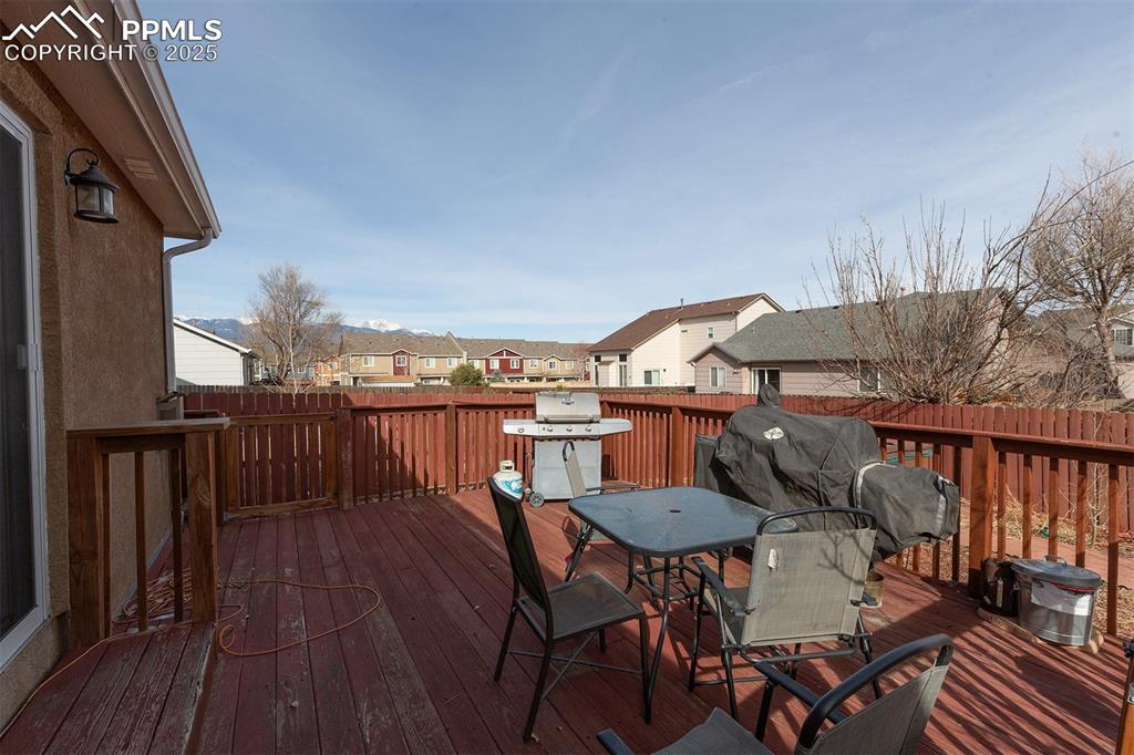 Image 11 of 12: Wooden terrace featuring a grill, outdoor dining area, fence, and a residen