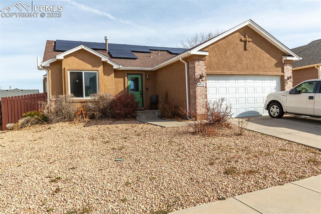 Image 2 of 12: Ranch-style home featuring fence, roof mounted solar panels, a garage, conc