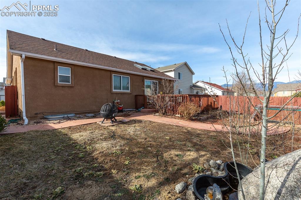 Image 9 of 12: Rear view of property with stucco siding, fence, and a shingled roof