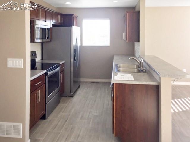 Image 3 of 19: Kitchen featuring a peninsula, stainless steel appliances, light countertop