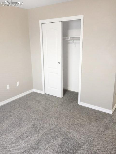 Image 8 of 19: Unfurnished bedroom with a closet and dark carpet