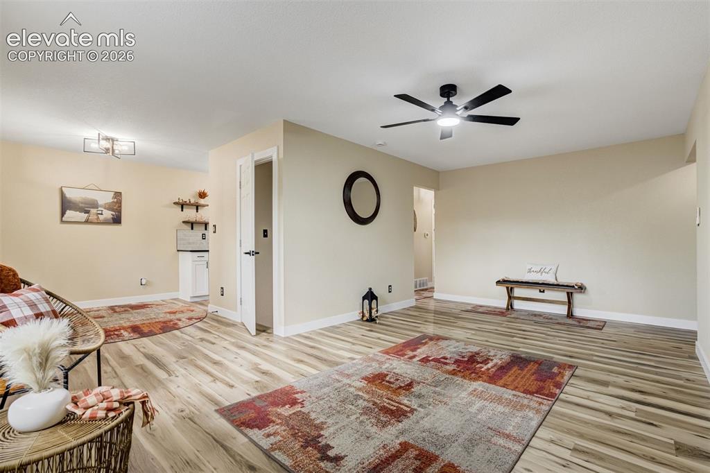 Image 11 of 50: Living room connects to the dining room and kitchen. Door leads to the full