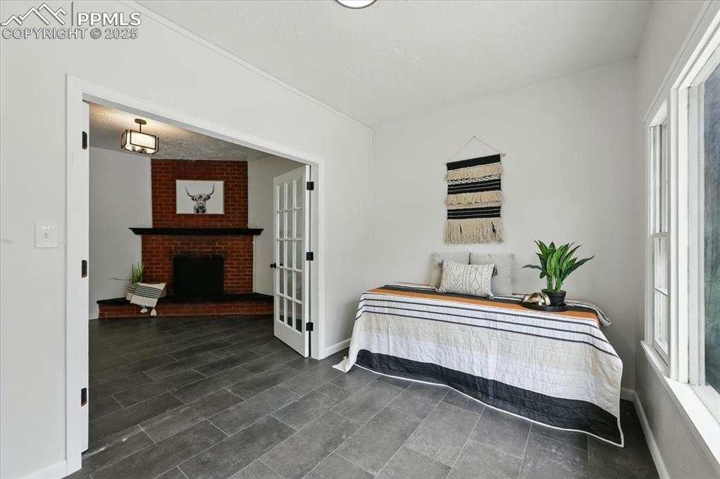 Image 12 of 32: Bedroom featuring multiple windows and a fireplace