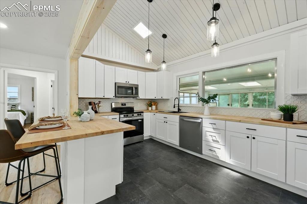 Image 20 of 32: Kitchen with stainless steel appliances, wooden counters, a breakfast bar a