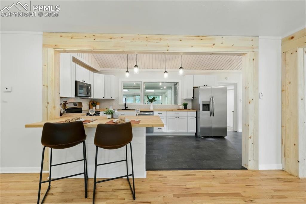 Image 21 of 32: Kitchen with stainless steel appliances, a peninsula, butcher block counter