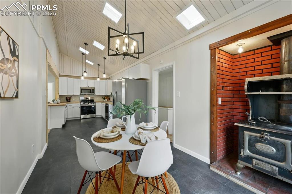 Image 26 of 32: Dining room featuring a wood stove, a chandelier, a skylight, crown molding