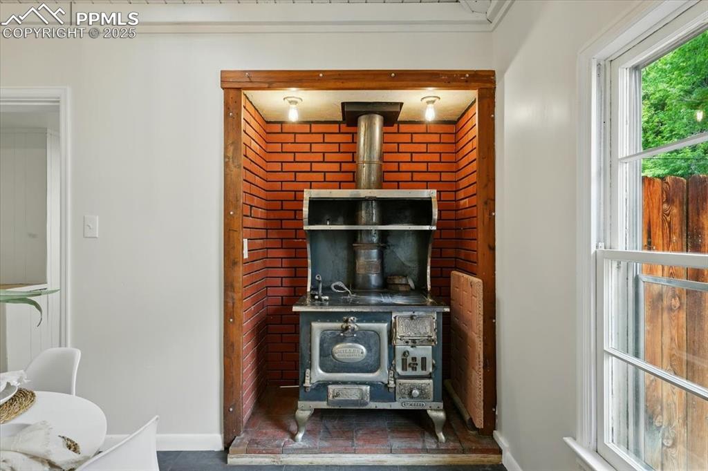 Image 27 of 32: Detailed view of a wood stove and baseboards