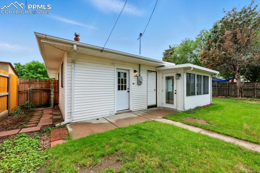 Image 31 of 32: Rear view of property with a fenced backyard, a sunroom, and a chimney