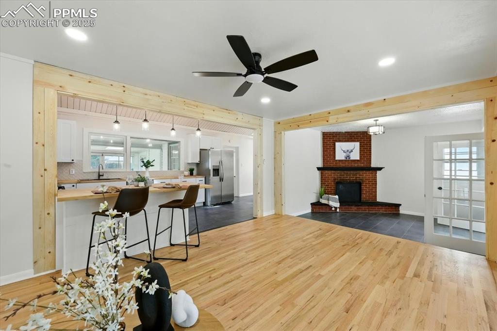 Image 7 of 32: Living room featuring dark wood-style flooring, ceiling fan, a fireplace, r