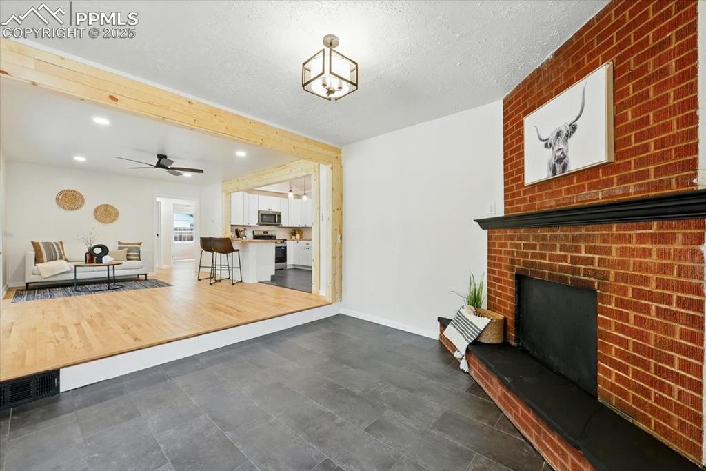 Image 9 of 32: Living room with a fireplace, a ceiling fan, recessed lighting, and a textu