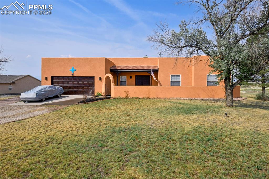 Caption: Southwest-style home featuring stucco siding, driveway, an attached garage, and a front yard