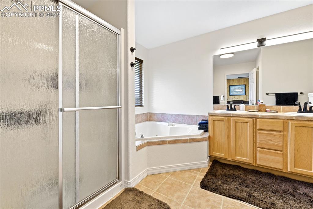 Image 12 of 22: Full bathroom with a shower stall, light tile patterned flooring, double va