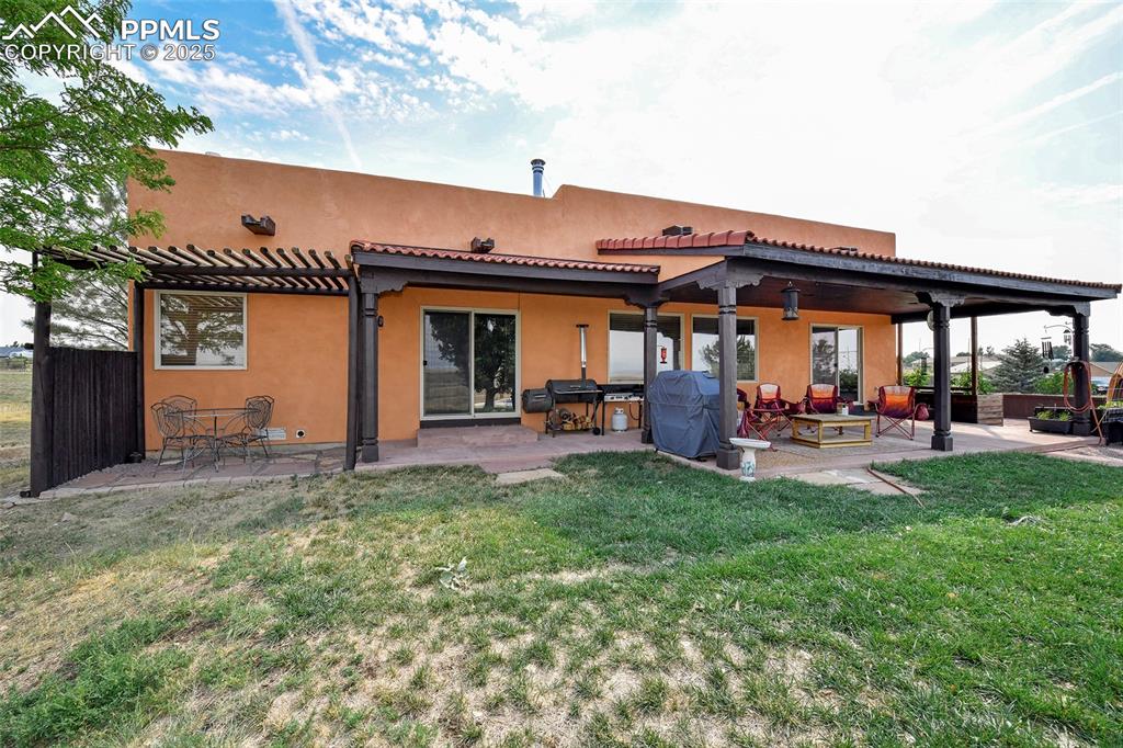 Image 16 of 22: Rear view of house featuring a lawn, stucco siding, and a patio area