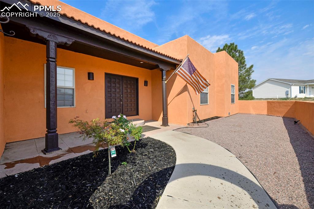 Image 2 of 22: View of exterior entry with stucco siding and a porch