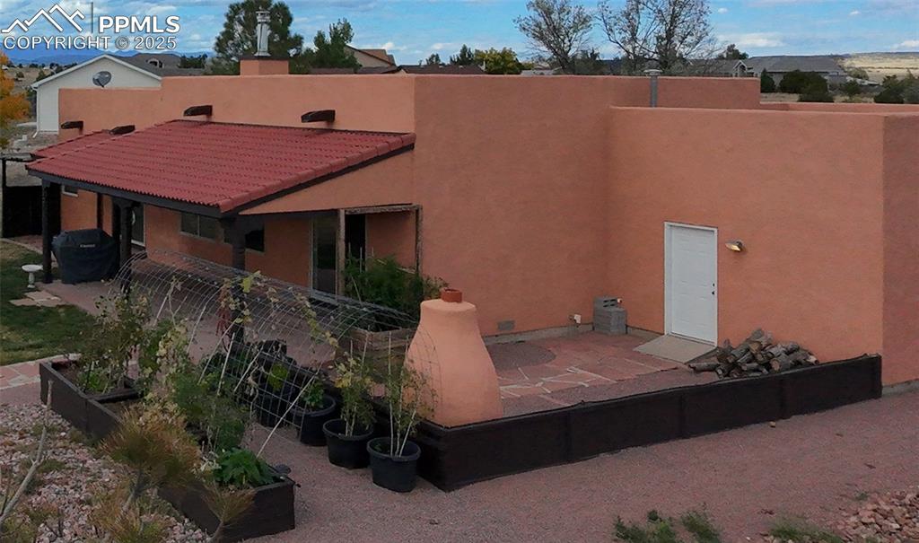 Image 24 of 32: Rear view of house with a patio, stucco siding, and a garden