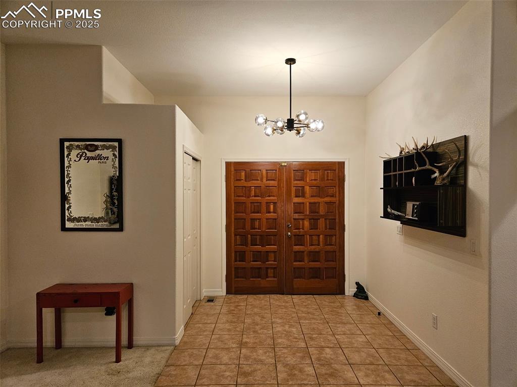 Image 28 of 32: Foyer entrance featuring a chandelier and light tile patterned floors