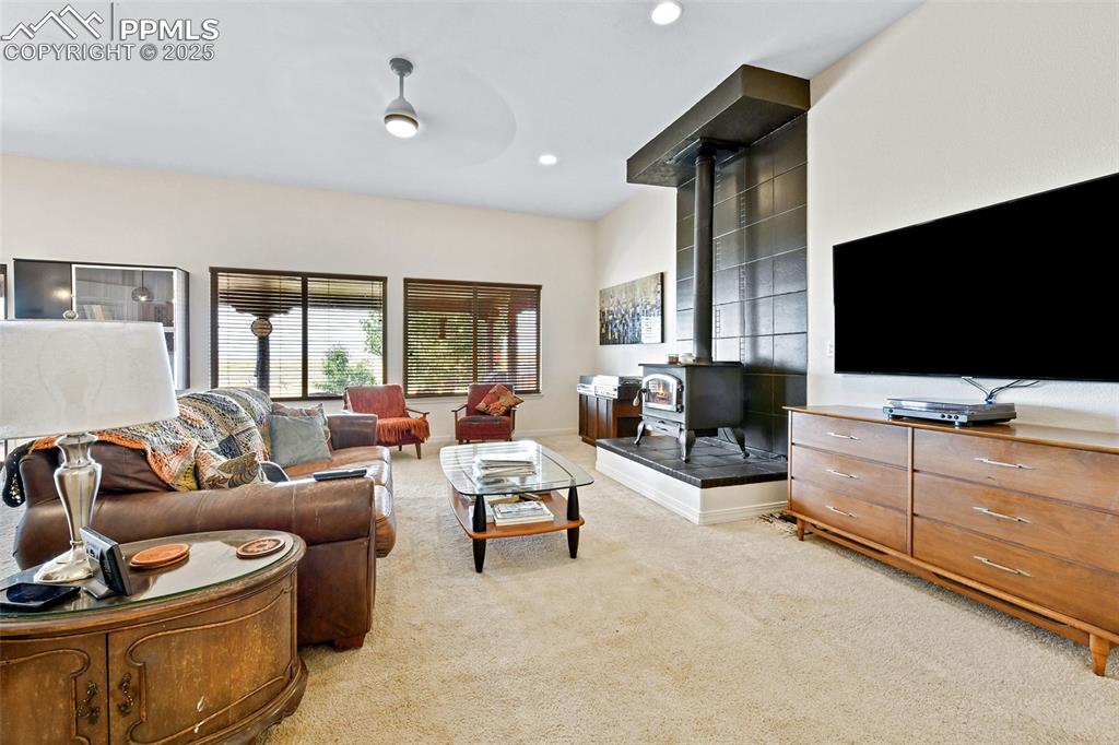 Image 4 of 22: Living room with a wood stove, light colored carpet, and recessed lighting