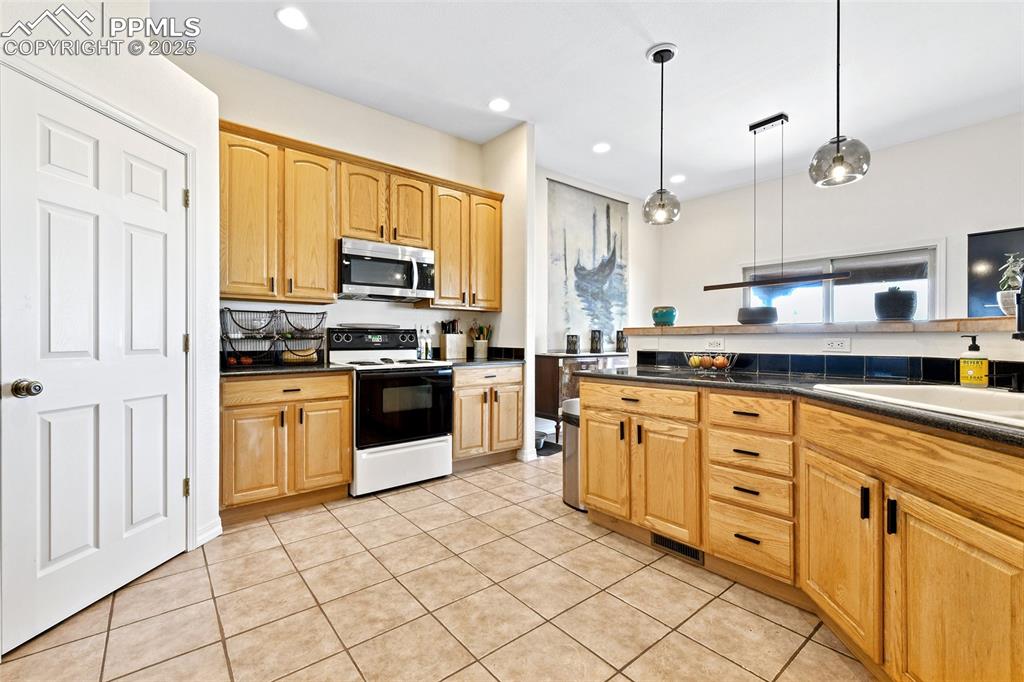 Image 8 of 22: Kitchen featuring white range with electric cooktop, pendant lighting, ligh