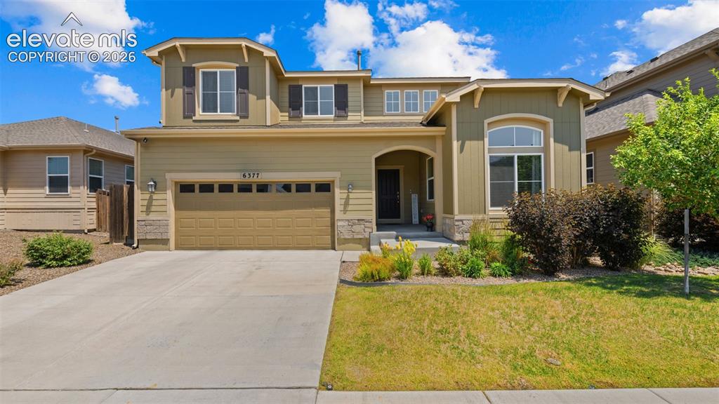 Image 1 of 45: Two-story residence featuring a two-car garage, stone accents, and a covere