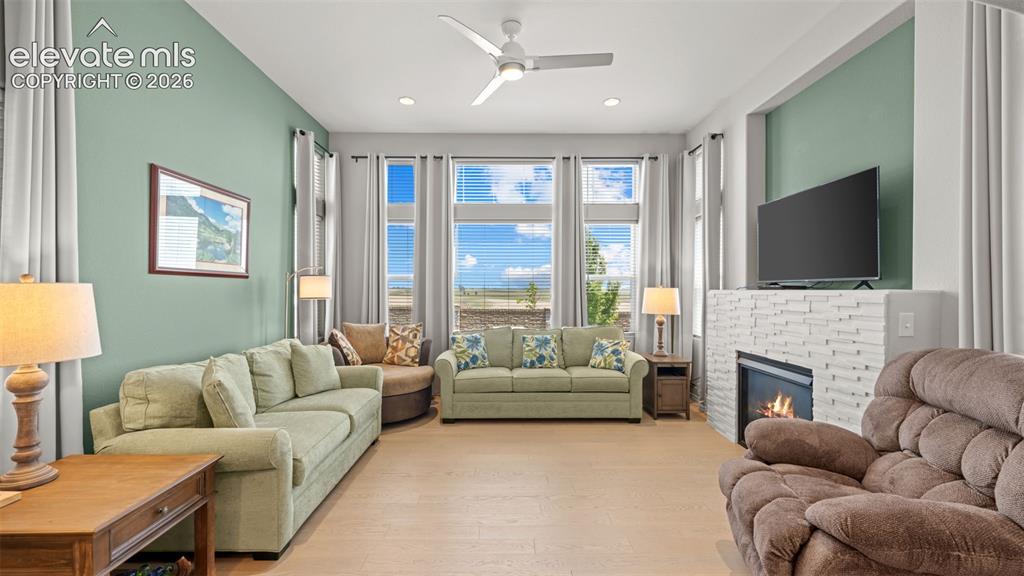 Image 10 of 45: Living area with wood-finish flooring, a contemporary ceiling fan, and a fi