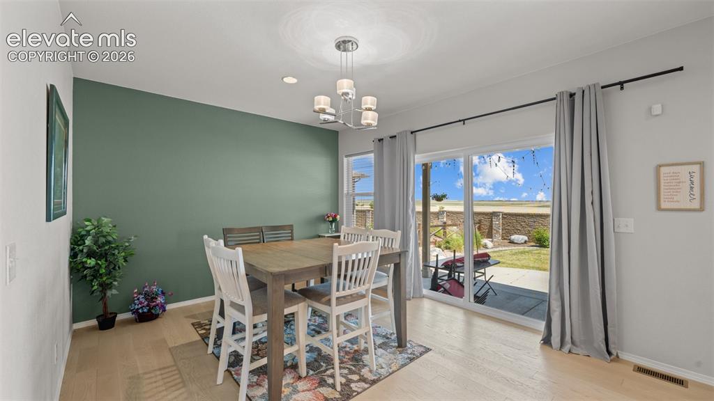 Image 12 of 45: Dining area featuring a contemporary chandelier, light wood-finish flooring