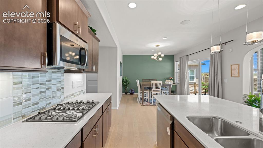 Image 14 of 45: Modern kitchen featuring dark wood cabinetry, white countertops, and a tile