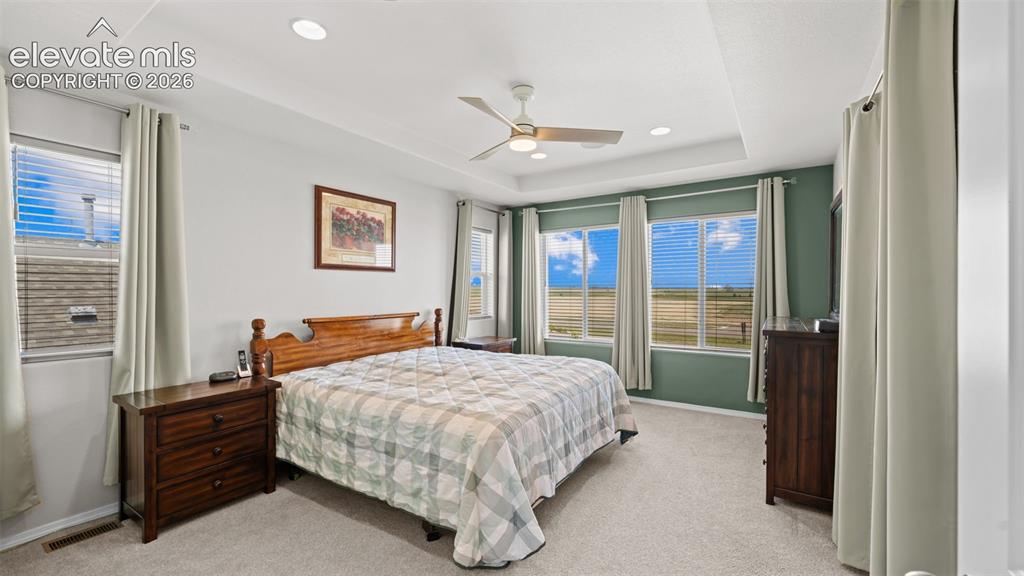 Image 26 of 45: Spacious bedroom with tray ceiling, recessed lighting, and multiple windows