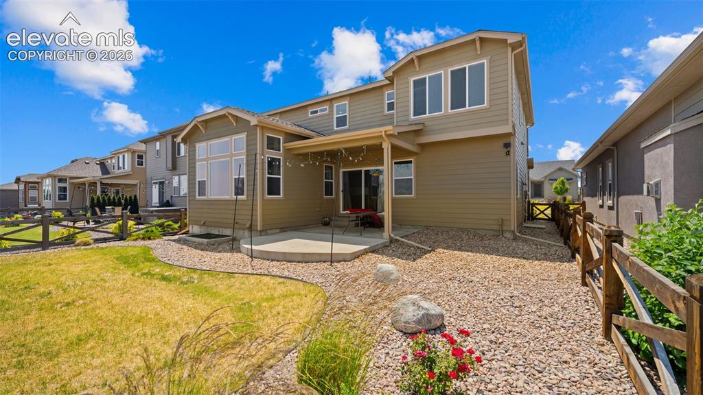 Image 33 of 45: Rear exterior featuring a covered patio, concrete slab, gravel landscaping,