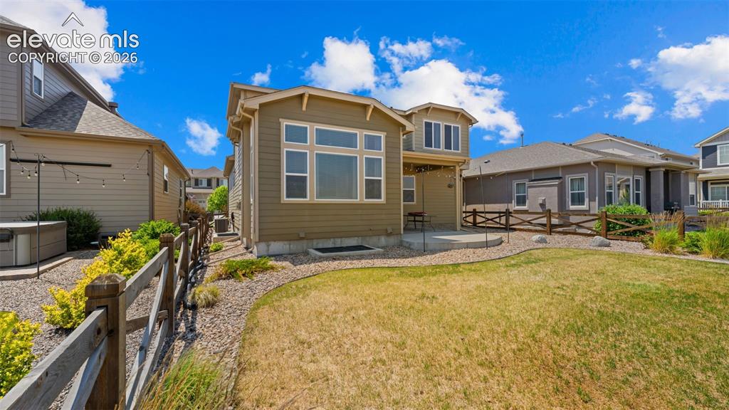 Image 34 of 45: Expansive rear yard featuring natural grass, a flagstone patio, and a decor