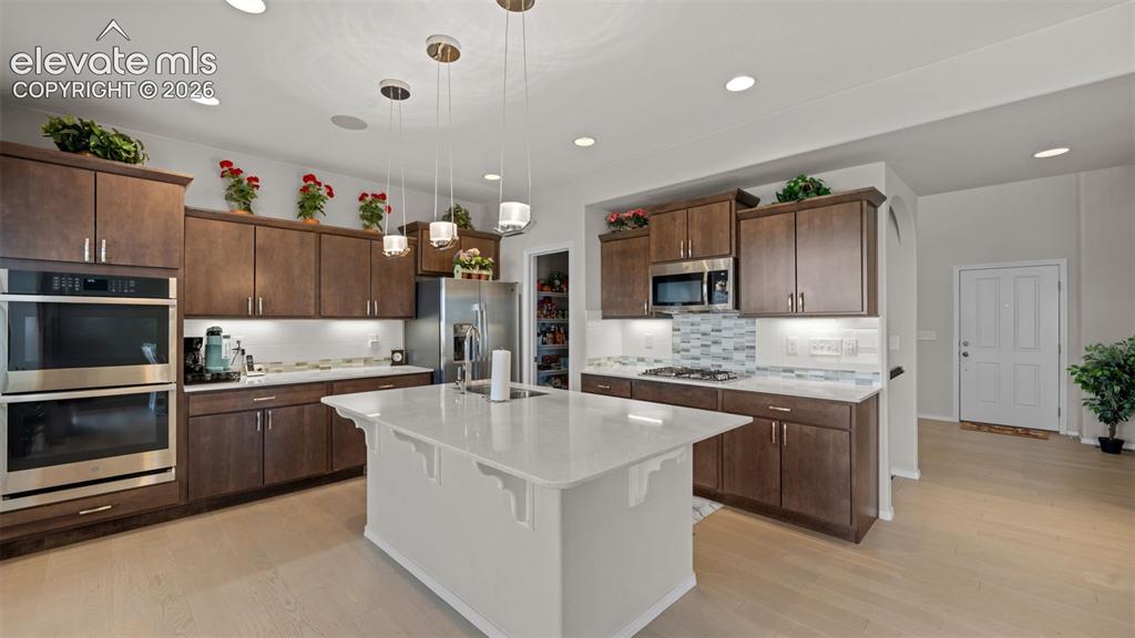 Image 8 of 45: Expansive kitchen featuring a large central island with a solid surface cou