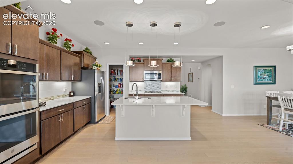 Image 9 of 45: Spacious kitchen featuring an expansive central island with seating, stainl