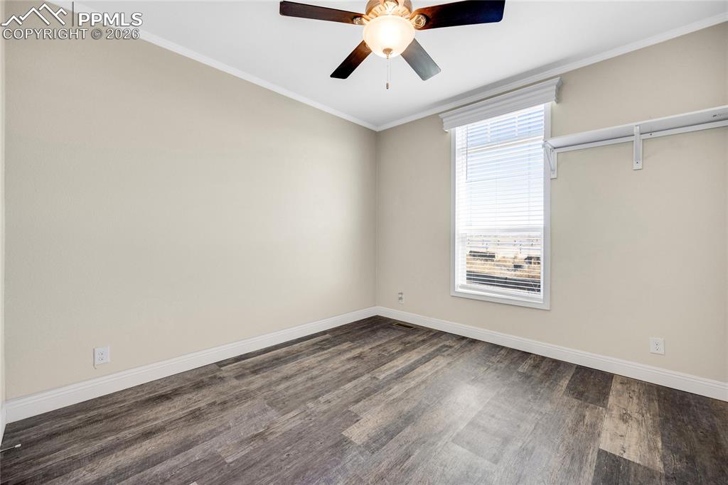 Image 49 of 50: Empty room featuring crown molding, dark wood-style floors, and ceiling fan