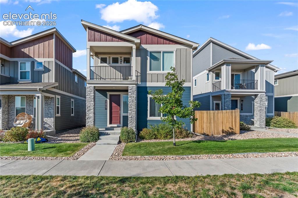 Caption: Modern architectural design with a prominent front balcony, stone veneer accents, wood-finish siding