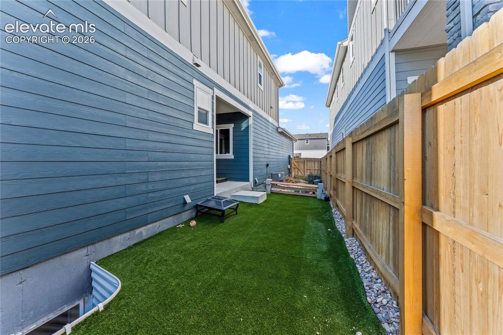 Image 17 of 17: Spacious backyard oasis featuring lush synthetic turf, wooden privacy fenci