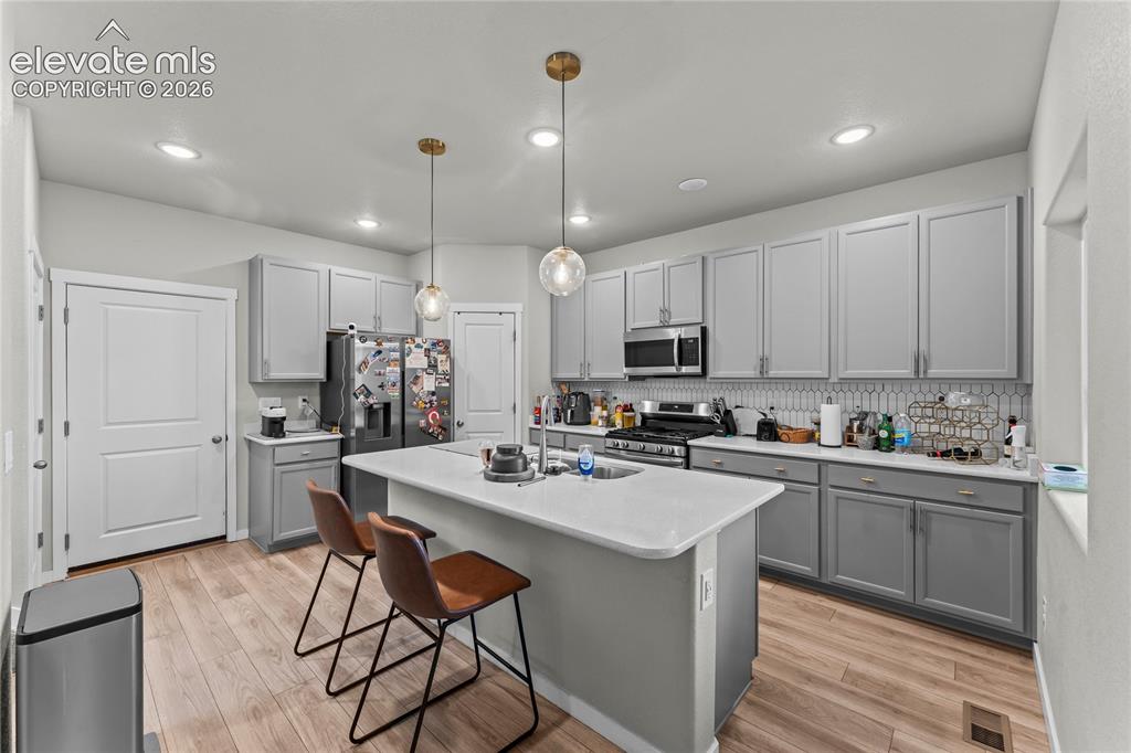 Image 6 of 17: Kitchen featuring light wood-finish flooring, gray cabinetry, a central isl