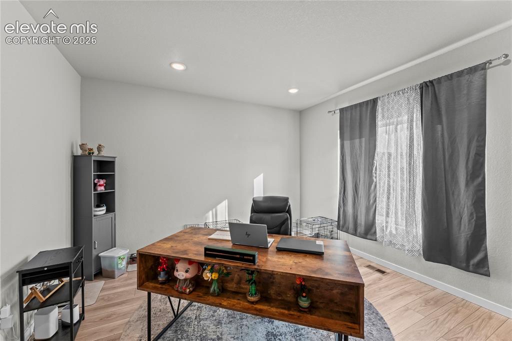 Image 8 of 17: Dedicated home office featuring warm wood-finish flooring, a spacious work 